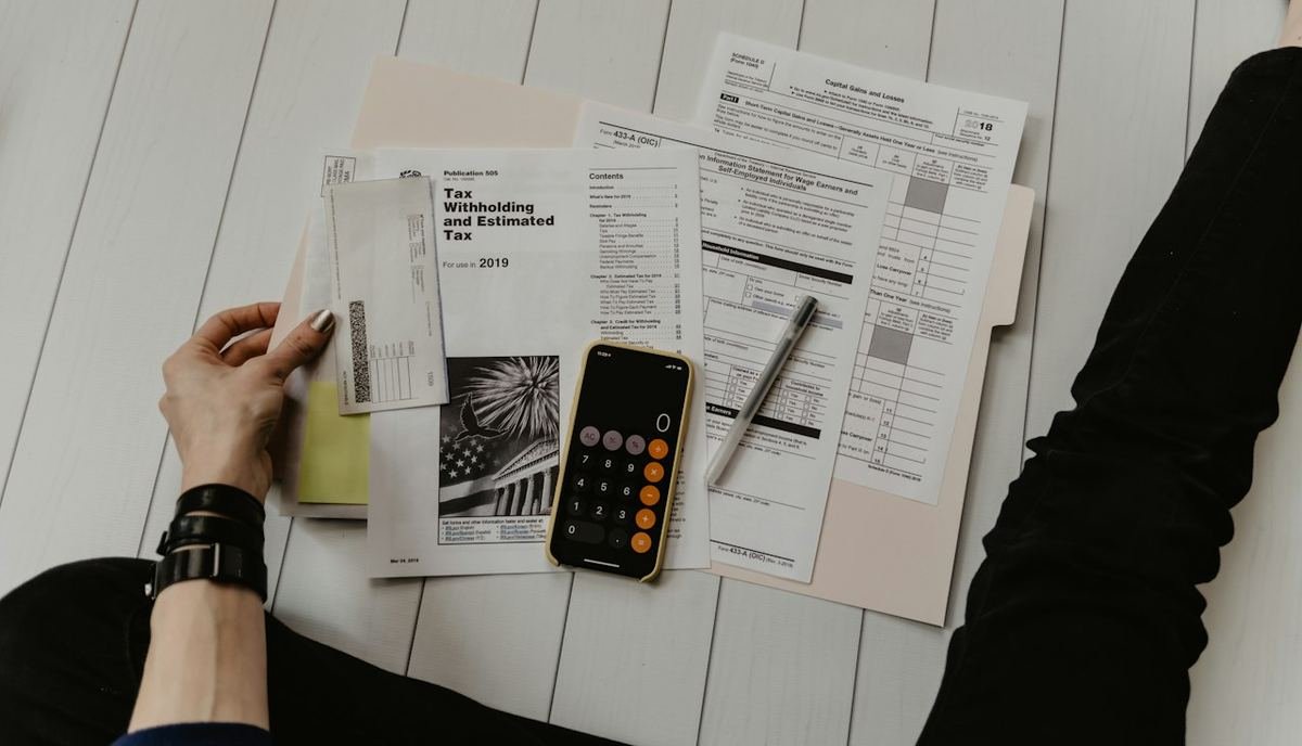 Hands reviewing trade documents with a calculator on a desk